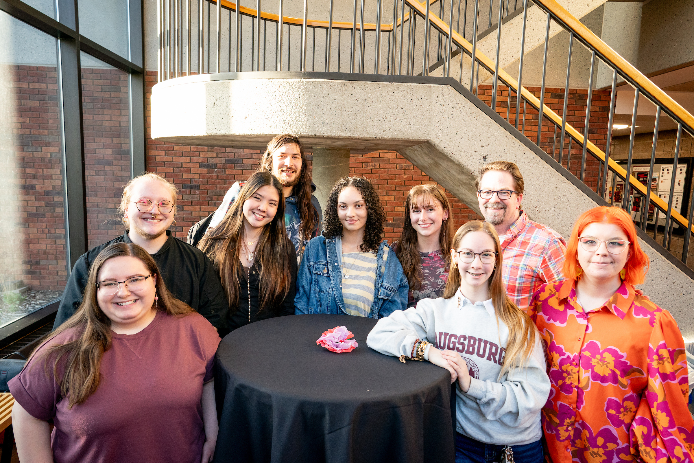 Group of students that worked together on the Tangled Roots project, gather around a round table.