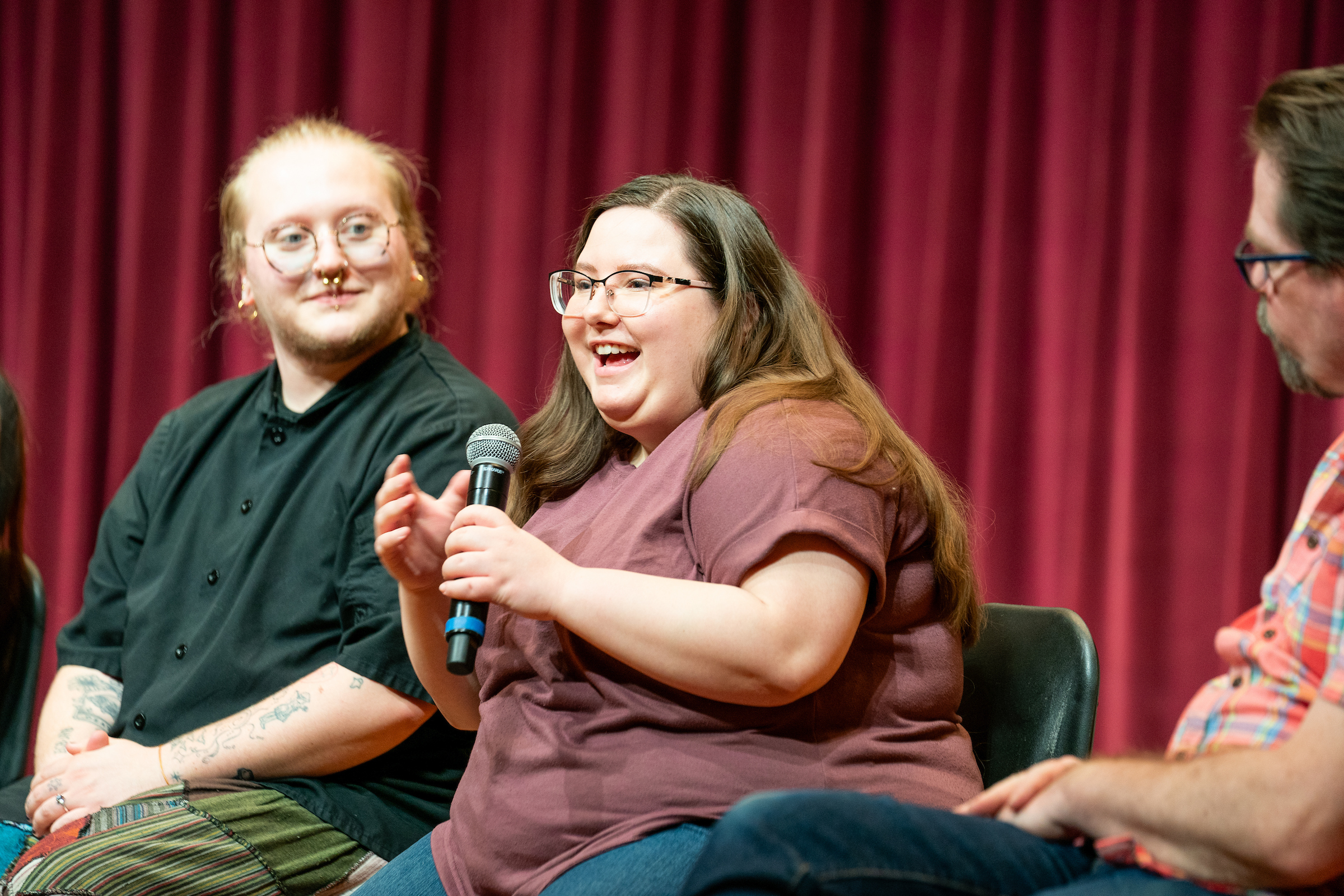 A student talks in to a microphone while other students look on.